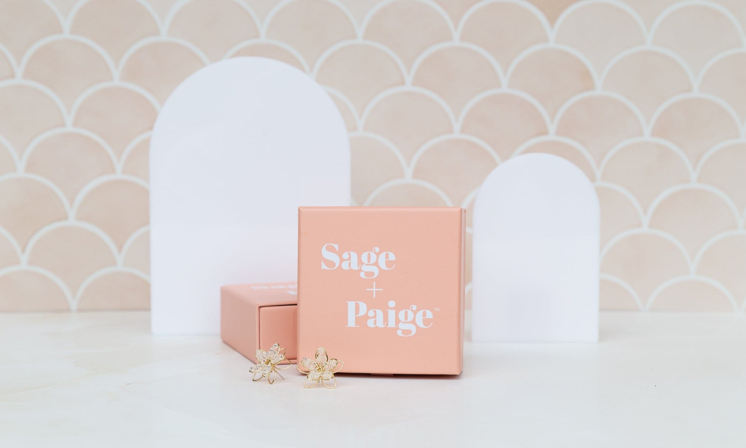 small and large acrylic arch shapes photographed against a peach fish scale tile with earrings - backdrop collective