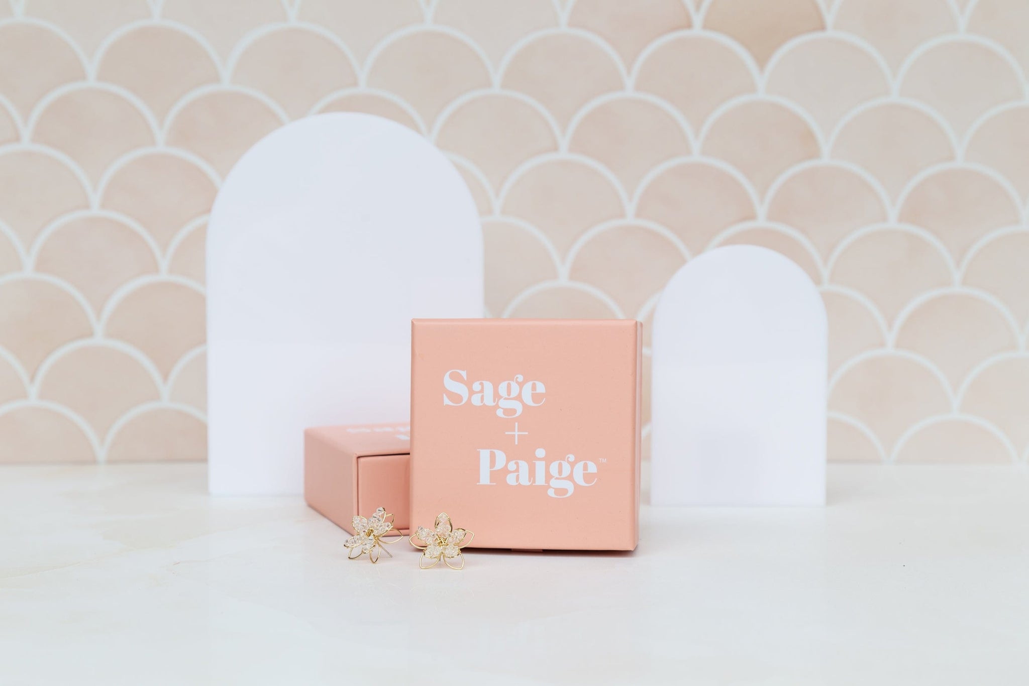 small and large acrylic arch shapes photographed against a peach fish scale tile with earrings - backdrop collective