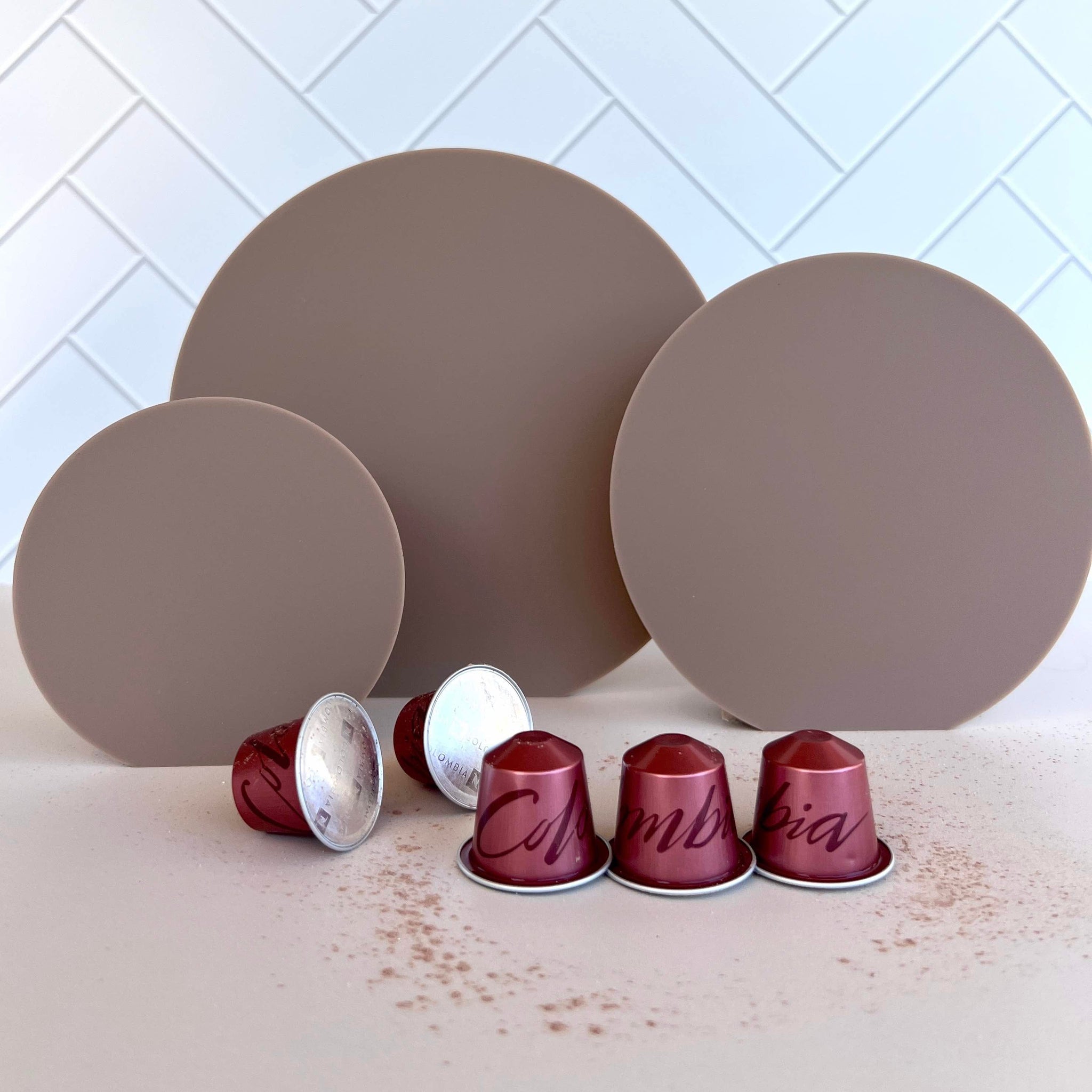 coffee coloured acrylic circle props with herringbone tile backdrop and Nespresso coffee pods - backdrop collective