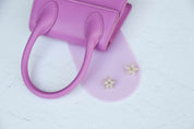 pink acrylic arch photographed with a pink handbag and earrings on a white concrete vinyl photography backdrop - backdrop collective australia