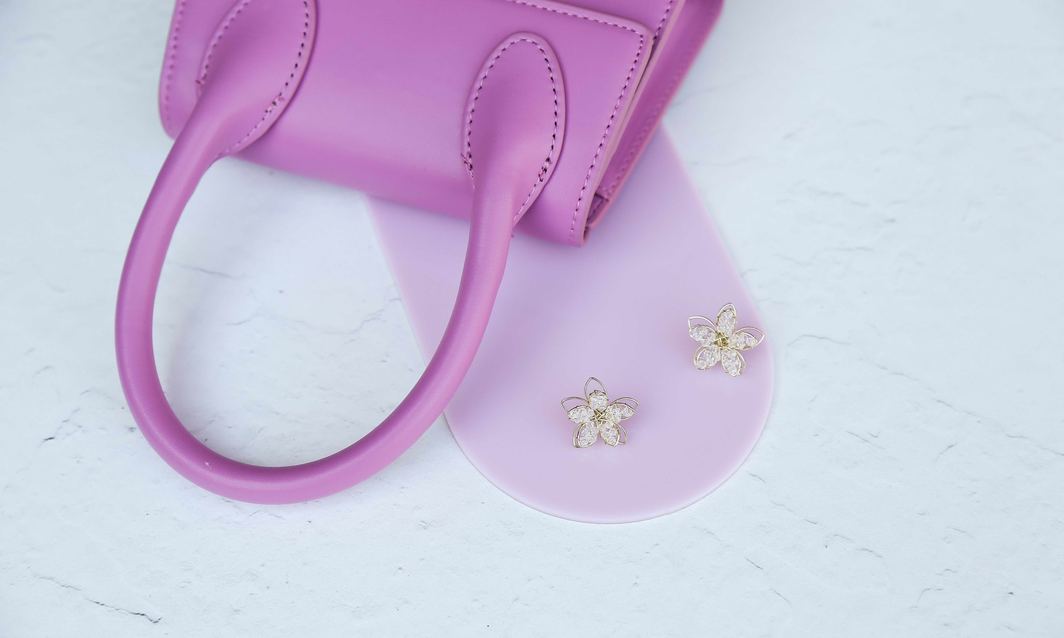 pink acrylic arch photographed with a pink handbag and earrings on a white concrete vinyl photography backdrop - backdrop collective australia