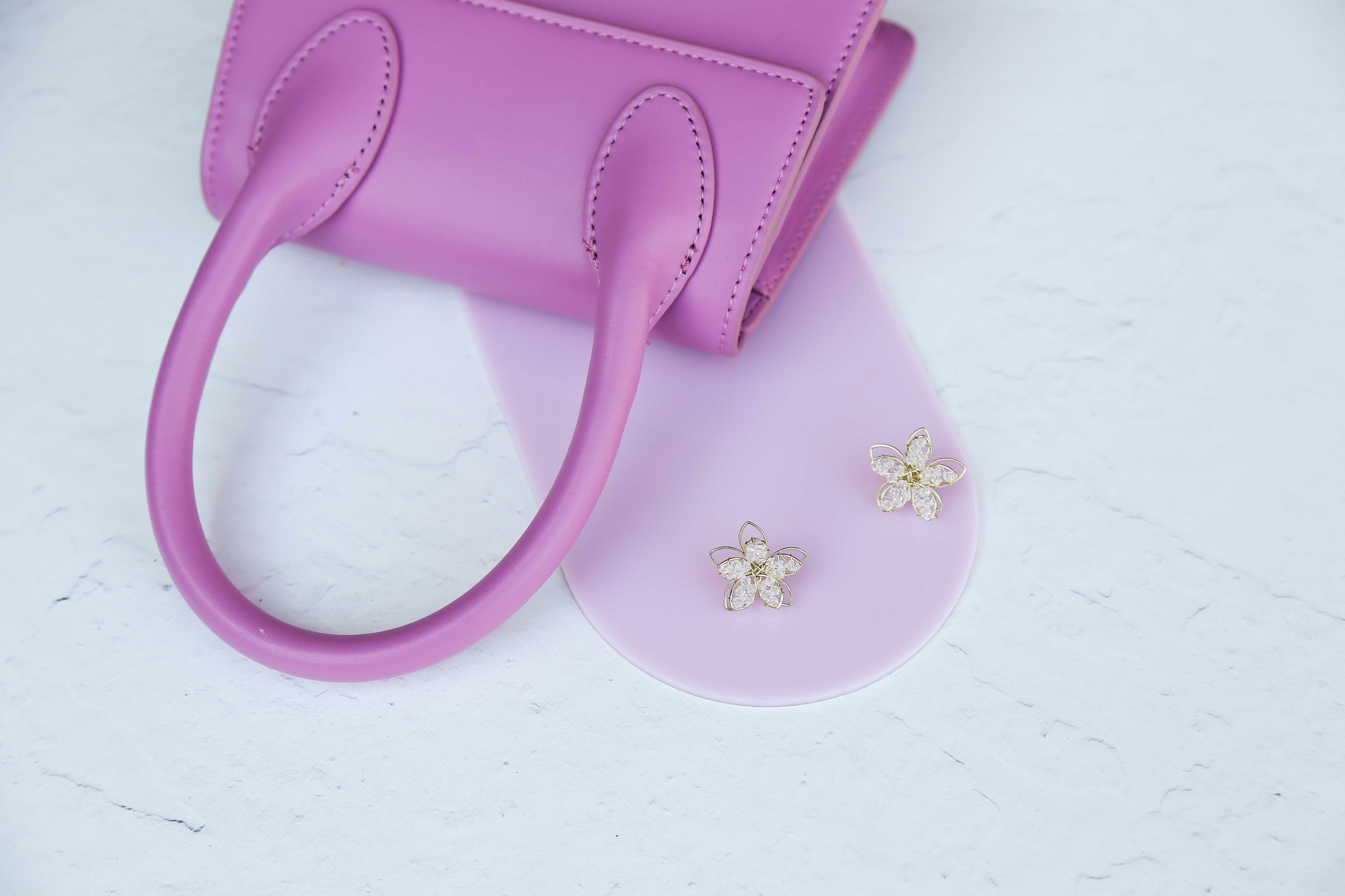pink acrylic arch photographed with a pink handbag and earrings on a white concrete vinyl photography backdrop - backdrop collective australia